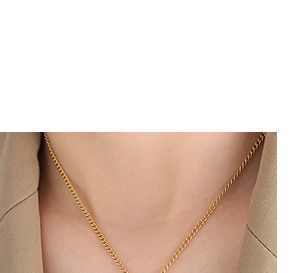 Detailed view of a slender gold chain necklace on a model wearing a khaki blazer