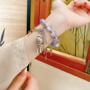 Close-up of stacked beaded flower bracelets with purple crystals and vintage silver charms