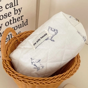 Quilted white cosmetic bag with cute blue bear patterns in a cozy woven basket