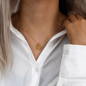 Golden stainless steel butterfly pendant necklace worn by a model on white shirt
