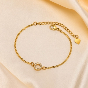 Detail of 18K gold bracelet with pave zircon round pendant on champagne silk fabric