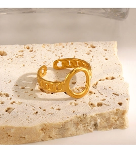 Close-up of gold hollow oval link ring on beige stone with soft aesthetic lighting