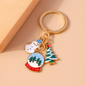 Christmas snowman and crystal ball keychain with enamel tree charms on peach background