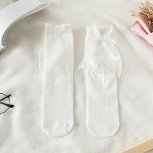 White crew socks featuring delicate lace edges and large sheer mesh bows on a soft background