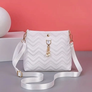 Detail of white quilted crossbody bag featuring V-pattern and pearl cat charm pendant