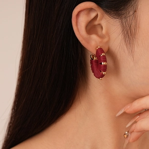 Close-up of vintage red woven hoop earrings with golden beads on a model