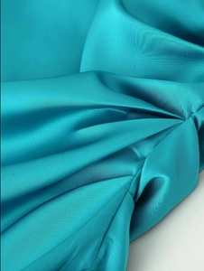 Détail macro du tissu satiné bleu sarcelle luxueux avec drapé élégant et brillant soyeux