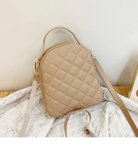 Detail of beige quilted mini backpack with PU leather texture and gold hardware on knit rug