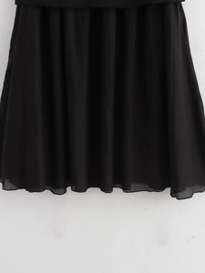 Detailed close-up of black pleated chiffon hem with fine textures and elegant draping