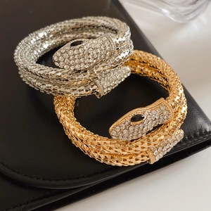 Macro shot of gold and silver snake bracelets with scale texture and crystal head