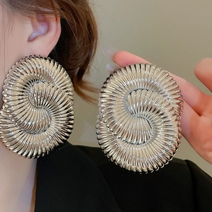 Close-up detail of silver geometric spiral earrings with textured metallic finish