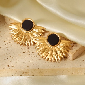 Detail of fan-shaped 18K gold leaf earrings with black stones on luxury silk backdrop
