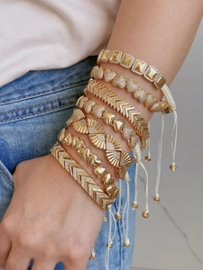 Detailopname van gelaagde gouden Boheemse armbanden met hart- en geometrische patronen