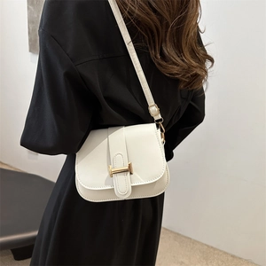Minimalist white leather square shoulder bag with gold H-buckle worn by a model in black