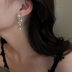 Detailed close-up of fringe earrings featuring white pearls and sparkling rhinestones