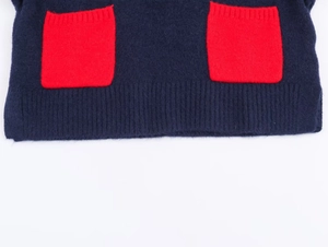 Close-up of navy knit top featuring large red square patch pockets and fuzzy texture