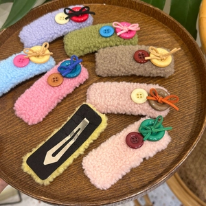Detail view of plush teddy fabric hair clips with colorful buttons and bow knots