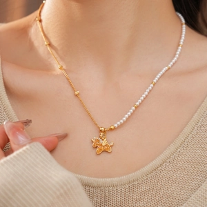 Detail of 18k gold plated unicorn necklace with pearls and zircon stones on a model