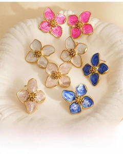 Vue à plat de boucles d'oreilles trèfle colorées à bords dorés sur un plateau