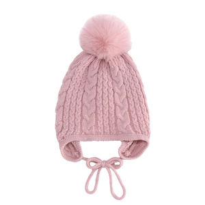 Detail of pink cable knit pattern and large faux fur pompom on baby winter earflap hat