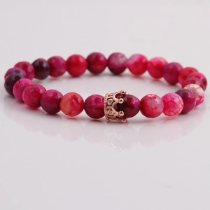 Macro detail of 8mm pink crackle stone beads bracelet with rose gold crown charm