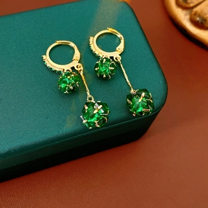 Detail of vintage gold hoop earrings with faceted green gemstone spheres and tassels