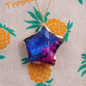 Macro detail of star-shaped blue glass pendant on a gold stainless steel chain