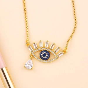 Detail of gold evil eye pendant necklace with blue stones and clear cubic zirconia charms