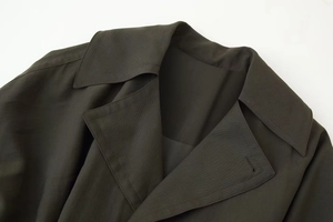 Gros plan du col de manteau vert olive foncé montrant la texture du tissu sergé et du revers