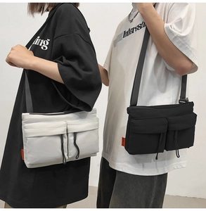Lifestyle shot of couple wearing black and cream nylon crossbody messenger bags with pockets