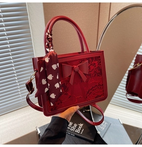 Macro detail of red bridal handbag with bow accent and decorative printed silk scarf