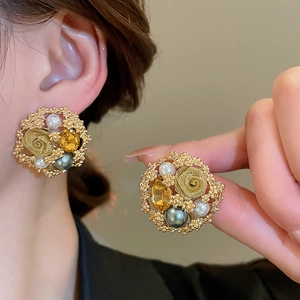 Detailed view of vintage gold floral earrings with pearls and a yellow crystal stone