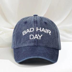 Detail shot of BAD HAIR DAY white embroidery on washed denim blue baseball cap