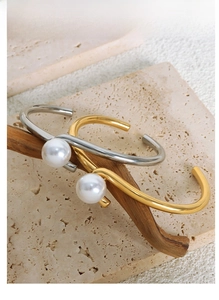Detailed view of high-gloss pearls on gold and silver plated titanium steel bracelets
