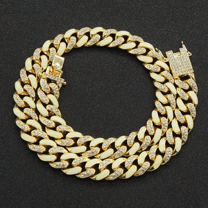Detail of gold Cuban link bracelet with white enamel inlay and sparkling rhinestones