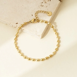 Detail of polished gold oval bead chain bracelet with lobster clasp and S.Steel tag