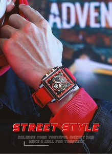 Close-up of a square skeleton sports watch with a red silicone strap and gear details