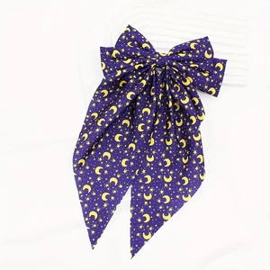 Detail of dark purple bow hair clip with yellow crescent moon and star print patterns