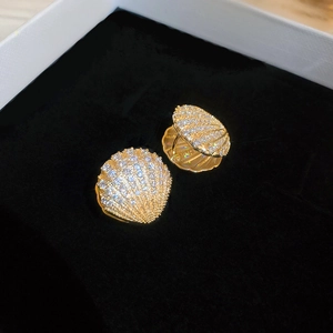 Detail showing shell-shaped earrings with gold plating and zircons in a jewelry box