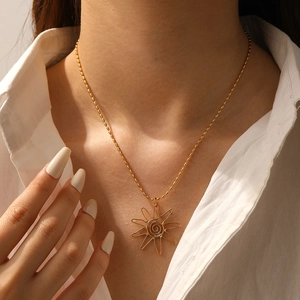 Close-up of a gold-plated necklace featuring a spiral sun pendant on a delicate bead chain