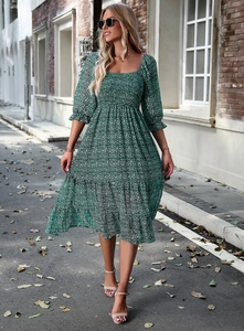 Green floral square neck dress with three-quarter sleeves in an outdoor street setting
