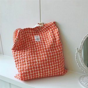 Detailed close-up of orange geometric plaid cotton tote bag with stitched woven label