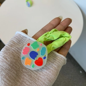 Close-up of a neon green scrunchie with a patterned acrylic charm on white background