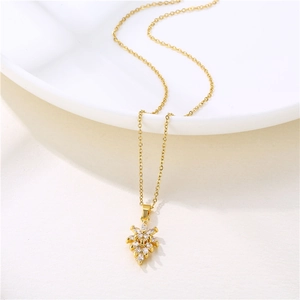 Collier à pendentif feuille d'érable dorée avec cristaux sur une assiette blanche épurée