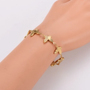 Polished gold butterfly charm bracelet with five textured pendants on a model hand