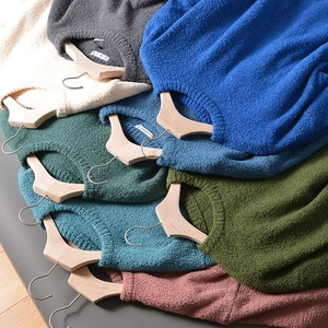 Detail view of multi-color crewneck sweaters with thick boucle knit texture on wooden hangers