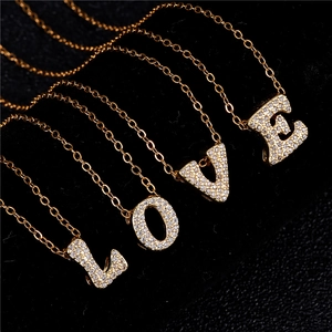 Detail of four gold necklaces with sparkling zircon pave letters spelling LOVE on black background
