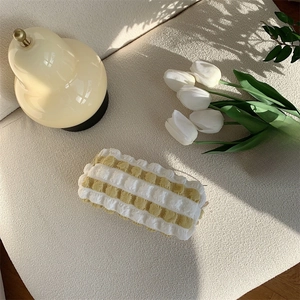 Detail of yellow and white striped popcorn texture pouch with soft bubble fabric design