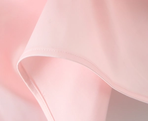 Close-up of the delicate stitching and smooth fabric texture on this light pink evening dress