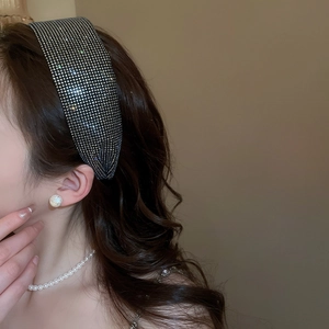 Close-up of elegant wide rhinestone headband worn with matching pearl jewelry